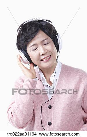 Picture - An elderly woman listening to the music with a headset on. Fotosearch
