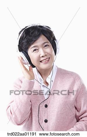An elderly woman listening to the music with a headset on View Large Photo Image Stock Image - An elderly woman listening to the music with a headset on. Fotosearch