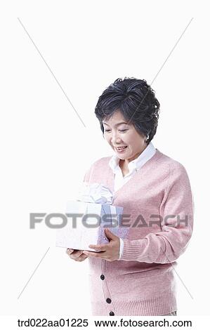 Stock Photography - An elderly woman looking down on the gift. Fotosearch