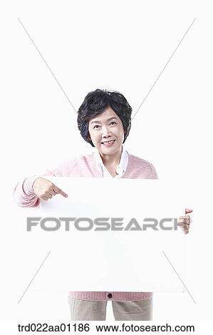 Stock Photograph - An elderly woman pointing to a white board. Fotosearch