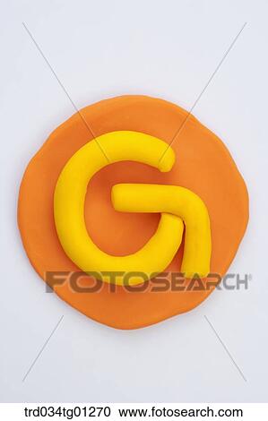 Stock Image - The alphabet G shaped yellow clay on the orange circle clay . Fotosearch