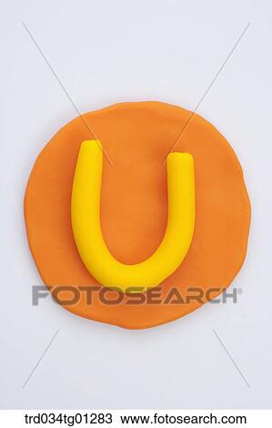 Stock Image - The alphabet U shaped yellow clay on the orange circle clay . Fotosearch
