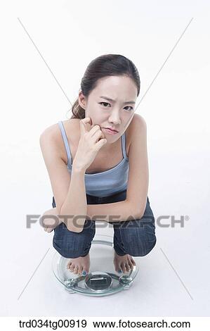 The annoyed woman on the weighing scale View Large Photo Image Stock Photo - The annoyed woman on the weighing scale. Fotosearch