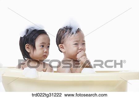 Stock Image - The babies taking a bath in the bathtub with the bubble on their bodies. Fotosearch