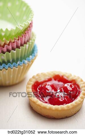 Stock Image - The colorful polka dots patterned baking cups and cherry jam tart. Fotosearch