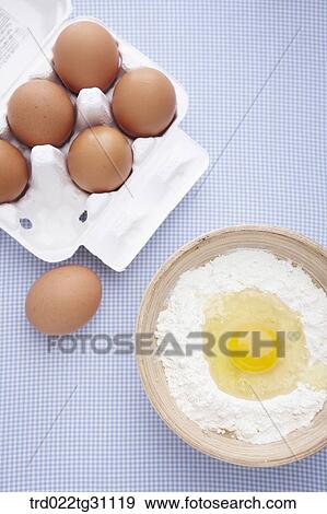 Stock Photo - The eggs in the carton and the egg in the bowl of flour. Fotosearch