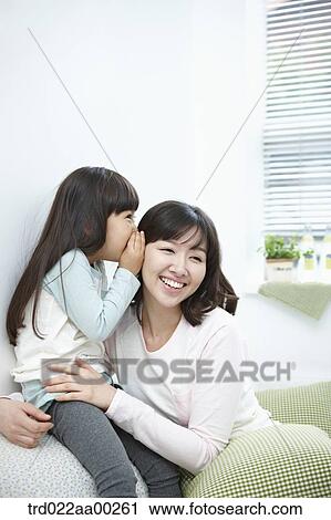 Stock Image - The girl whispering in woman's ear. Fotosearch