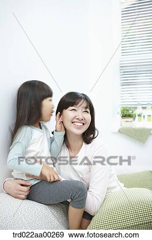 Stock Photo - The girl whispering in woman's ear. Fotosearch