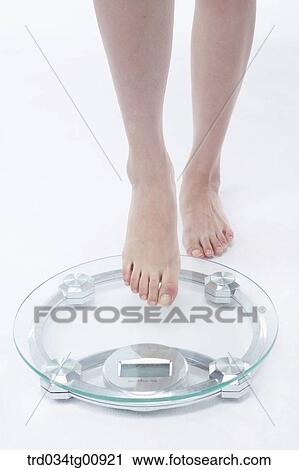 Stock Image - The legs touching on the weighing scale. Fotosearch