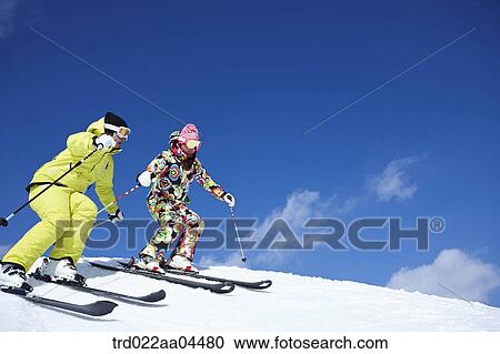 Stock Image - The man and woman skiing on the slope. Fotosearch
