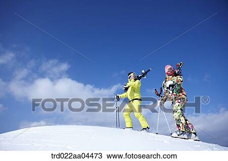 Stock Image - The man and woman wearing skiwear with the ski gear. Fotosearch