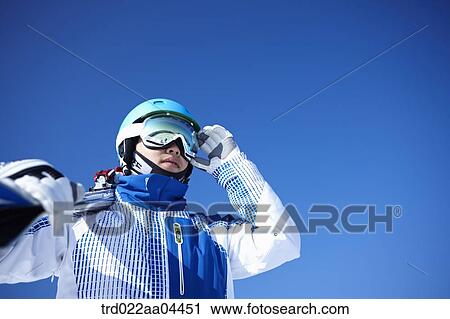 The man wearing skiwear with the ski boards on his shoulder View Large Photo Image Stock Image - The man wearing skiwear with the ski boards on his shoulder. Fotosearch
