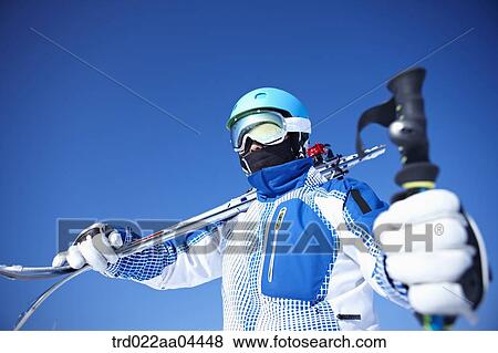 Stock Photo - The man wearing skiwear with the ski poles and ski boards. Fotosearch