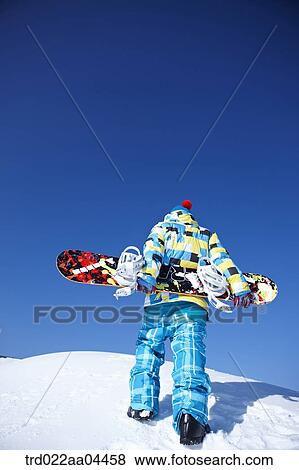 Stock Photo - The man wearing snowboarding wear with the snowboard. Fotosearch