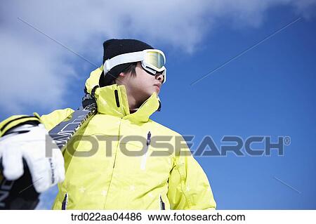 Stock Photograph - The man with the ski boards on his shoulder. Fotosearch