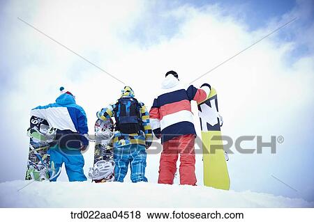 Stock Photo - The people wearing the snowboarding wear with the snowboards. Fotosearch