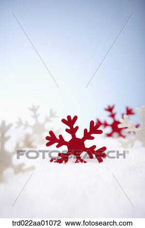 Stock Image - The red and white snowflake on the snow. Fotosearch