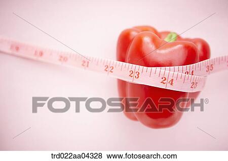 Stock Photo - The red bell pepper tied with the tape measure. Fotosearch