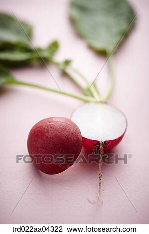 Stock Image - The red turnip in half and green leaves with the pink background. Fotosearch