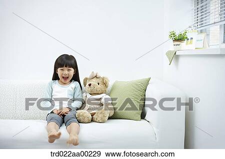 Stock Photo - The smiling girl on the white couch . Fotosearch