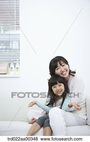 Stock Photo - The smiling woman and girl on the couch. Fotosearch