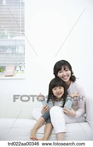 Stock Photograph - The smiling woman and girl on the couch. Fotosearch