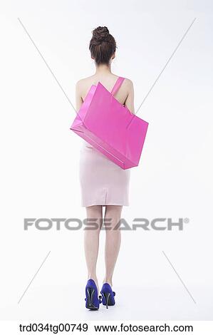Stock Photo - The smiling woman holding shopping bag from the back. Fotosearch