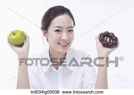 The smiling woman with an apple and a doughnut on each hand View Large Photo Image Stock Photo - The smiling woman with an apple and a doughnut on each hand. Fotosearch