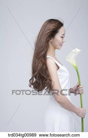 Stock Photo - The smiling woman with white flower. Fotosearch