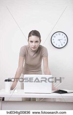 Stock Photograph - The standing woman having her hands on the desk. Fotosearch