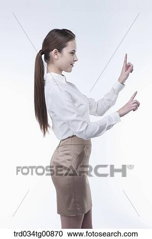 Stock Image - The standing woman with her pointing fingers from the side. Fotosearch