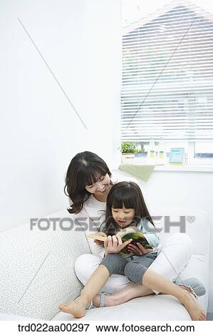 Stock Photo - The woman and girl reading a book together. Fotosearch