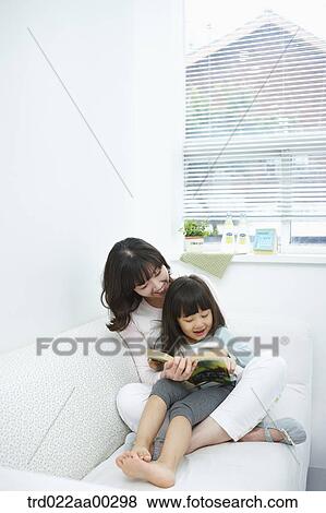 Stock Photo - The woman and girl reading a book together. Fotosearch