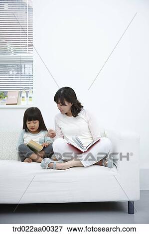 The woman and girl reading a book together on the couch View Large Photo Image Stock Photo - The woman and girl reading a book together on the couch. Fotosearch