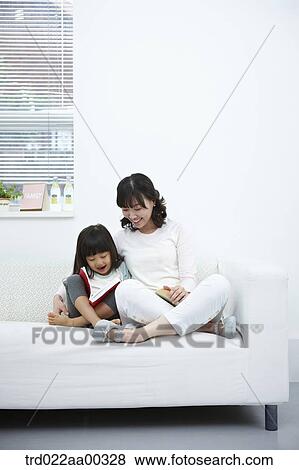 The woman and girl reading a book together on the couch View Large Photo Image Stock Photo - The woman and girl reading a book together on the couch. Fotosearch
