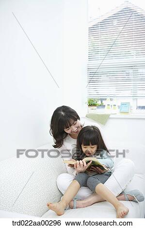 Stock Photograph - The woman and girl reading a book together. Fotosearch