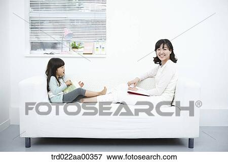 The woman and girl sitting on the couch with the book View Large Photo Image Stock Photo - The woman and girl sitting on the couch with the book. Fotosearch