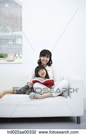 Stock Image - The woman and girl smiling together with a book. Fotosearch