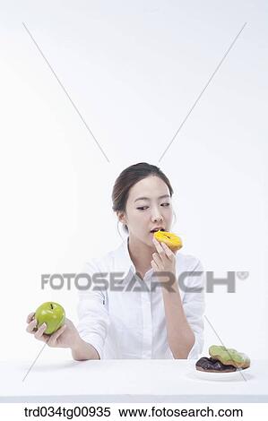 The woman having a doughnut with an apple on another hand View Large Photo Image Stock Photography - The woman having a doughnut with an apple on another hand. Fotosearch