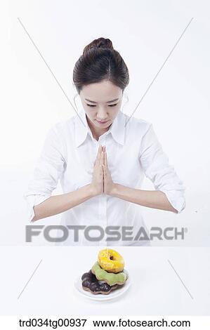 Stock Photo - The woman having her hands together over the doughnuts. Fotosearch