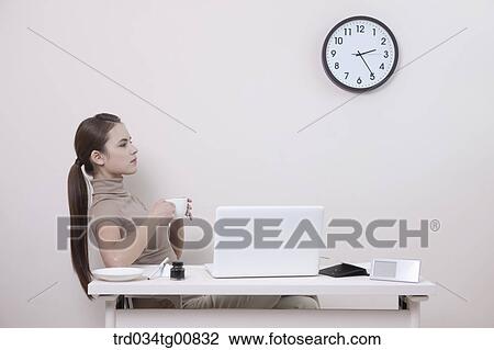 The woman holding a cup of coffee in the office View Large Photo Image Stock Image - The woman holding a cup of coffee in the office. Fotosearch