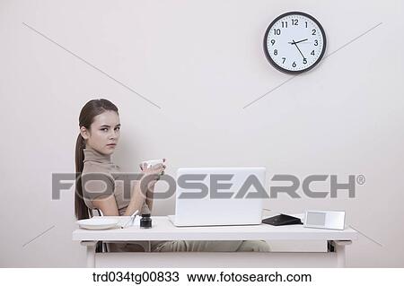 The woman holding a cup of coffee in the office View Large Photo Image Stock Image - The woman holding a cup of coffee in the office. Fotosearch