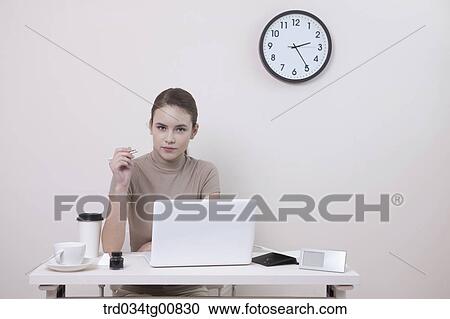 Stock Image - The woman holding a pen in the office. Fotosearch