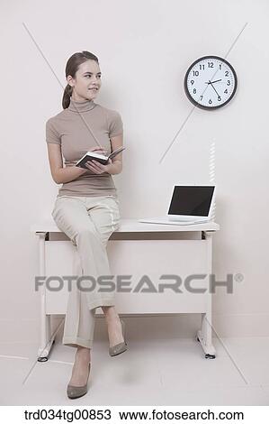 Stock Image - The woman holding pen and planner on the desk. Fotosearch