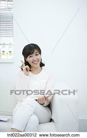 The woman holding the pencil and notebook with her finger up View Large Photo Image Stock Image - The woman holding the pencil and notebook with her finger up . Fotosearch