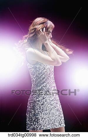 Stock Photo - The woman in glittering dress having her hands on the ear. Fotosearch