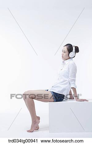 Stock Image - The woman listening to music with the headphone on . Fotosearch