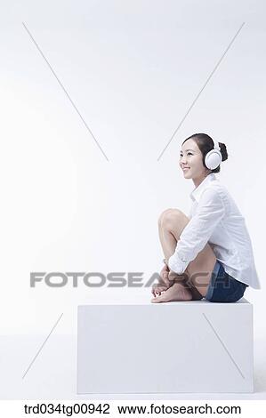 Stock Image - The woman listening to music with the headphone on . Fotosearch