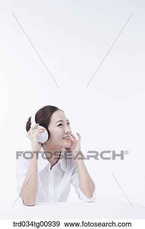 Stock Photo - The woman listening to music with the headphone on . Fotosearch