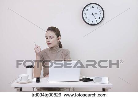 Stock Photo - The woman looking at a pen in the office. Fotosearch